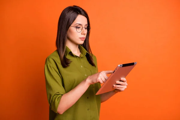 Foto retrato de la morena freelancer enfocada trabajando mecanografiando en la tableta aislada sobre fondo de color naranja vivo — Foto de Stock