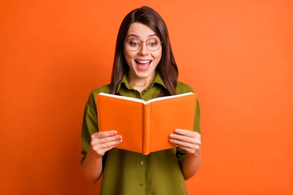 Fotoporträt von erstaunt glücklich Studentin trägt Brille Lesebuch lächelnd isoliert auf leuchtend orangefarbenem Hintergrund — Stockfoto