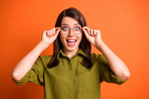 Foto retrato de sorprendida trabajadora sorprendida tocando gafas abiertas boca aislada sobre fondo de color naranja vivo — Foto de Stock
