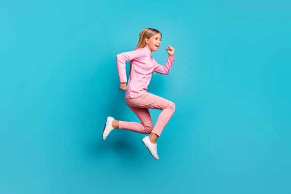 Profiel volledige lengte foto van schattig positief tienermeisje springen dragen roze broek poloneck witte schoenen geïsoleerd op teal achtergrond — Stockfoto