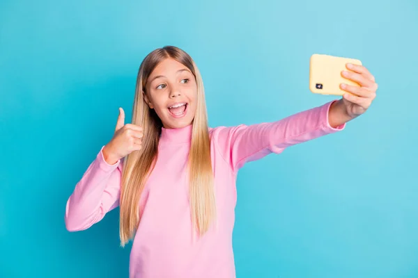 Parlak deniz mavisi arkaplanında izole edilmiş gibi baş parmak hareketi gösteren selfie çeken güzel bir kız çocuğunun fotoğrafı. — Stok fotoğraf