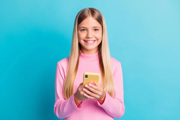 Photo portrait of happy schoolgirl holding smartphone smiling cheerfully isolated on vibrant teal color background — Stock Photo, Image