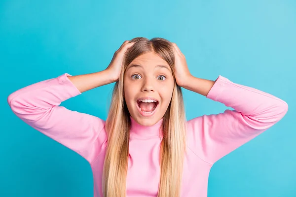 Photo portrait of shocked amazed blonde little girl shouting holding head with hands isolated on bright turquoise color background