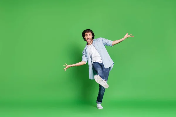 Uzun boylu, kıllı, komik, ağzı açık bir adamın fotoğrafı. Kot gömlek, kot pantolon, izole edilmiş yeşil arka plan. — Stok fotoğraf
