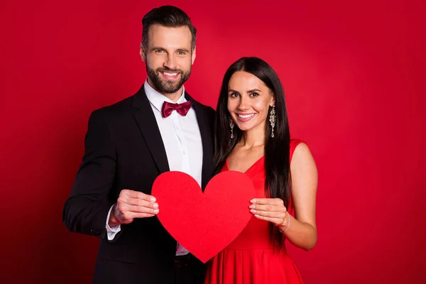 Foto di due belle persone braccia tenere grande cuore simbolo carta di carta dente sorriso isolato su sfondo di colore rosso — Foto Stock