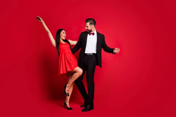 Photo of optimistic couple dance wear vivid dress black suit isolated on red color background — Stock Photo, Image