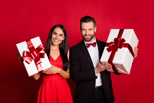 Tatlı iyimser çift hediyelerinin fotoğrafı kırmızı arka planda izole edilmiş bir elbise giyiyor. — Stok fotoğraf