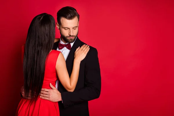 Foto de otimista agradável casal dança perto de espaço vazio desgaste terno vestido isolado no fundo de cor vermelha — Fotografia de Stock