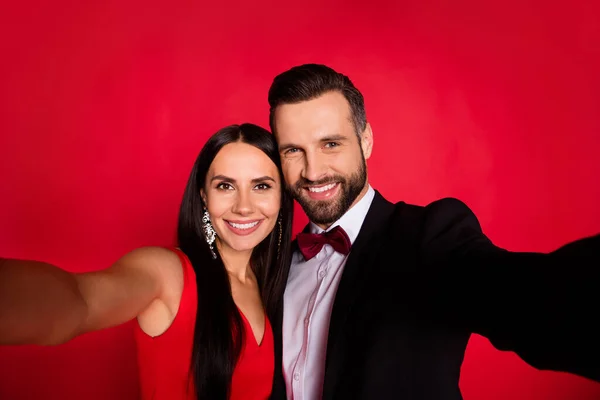 Foto de optimista linda pareja hacer selfie desgaste traje vestido aislado sobre fondo de color rojo —  Fotos de Stock