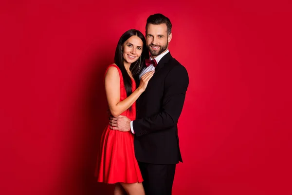 Фотографія профілю оптимістичної пари, що обіймає сукню костюма ізольовано на червоному тлі — стокове фото