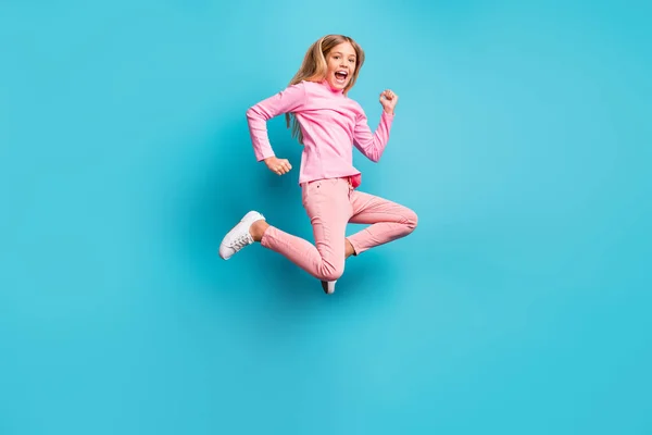 Фотографія повного розміру здивована красивою дівчинкою-підлітком, стрибає повітрям у рожеві штани, біле взуття полонека, ізольоване на яскравому сльозоточивому фоні — стокове фото