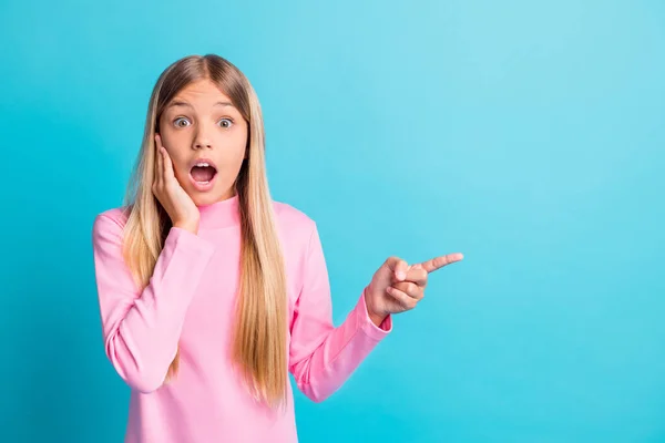 Fotoporträt von schockierten erstaunt kleines Mädchen zeigt mit dem Finger zeigt Kopierraum Berührung Wange isoliert auf lebendigen teal Farbhintergrund — Stockfoto