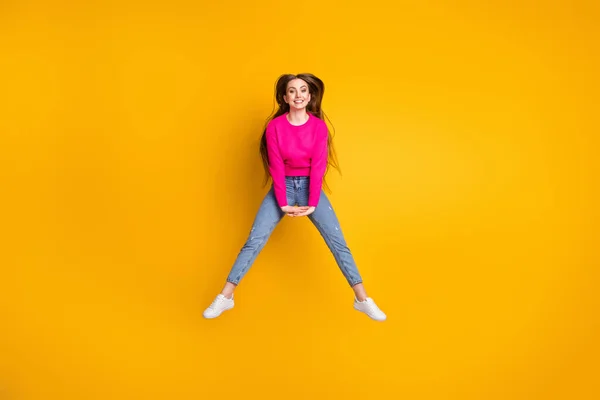 Volledige foto van charmante jonge vrouw spring hold handen dragen roze pullover jeans sneakers geïsoleerde gele kleur achtergrond — Stockfoto