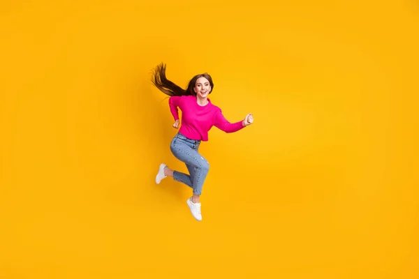 Volledige lengte profiel foto van mooie jonge meisje spring wind lang kapsel dragen roze trui jeans sneakers geïsoleerde gele kleur achtergrond — Stockfoto
