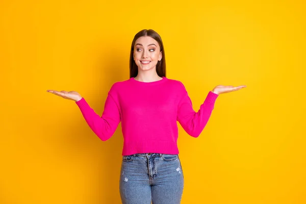 Фото юной леди поднять две руки держать смотреть пустое пространство носить розовые джинсы пуловер изолированный желтый цвет фона — стоковое фото