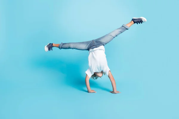 Small kid stand hands do acrobatic trick wear white shirt jeans sneakers isolated blue color background — Stock Photo, Image