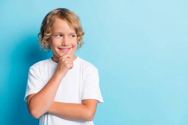 Foto de criança pequena mão queixo rosto encaracolado penteado radiante sorriso olhar vazio espaço desgaste branco camisa isolado azul cor fundo — Fotografia de Stock