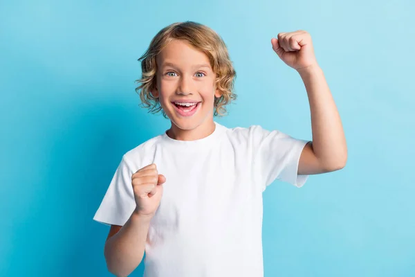 Foto van blij jongen verhogen vuisten dragen casual stijl kleding geïsoleerd over blauwe kleur achtergrond — Stockfoto