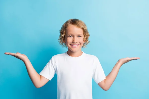 Foto de niño positivo cogido de las manos pesan espacio vacío usan ropa blanca aislada sobre fondo de color azul — Foto de Stock