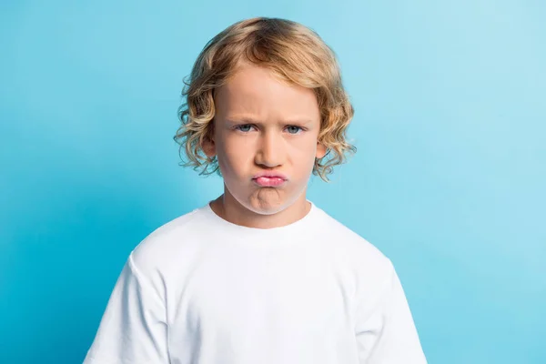 Photo de petit garçon avec visage grimace se sentir déçu porter t-shirt blanc isolé sur fond de couleur bleue — Photo
