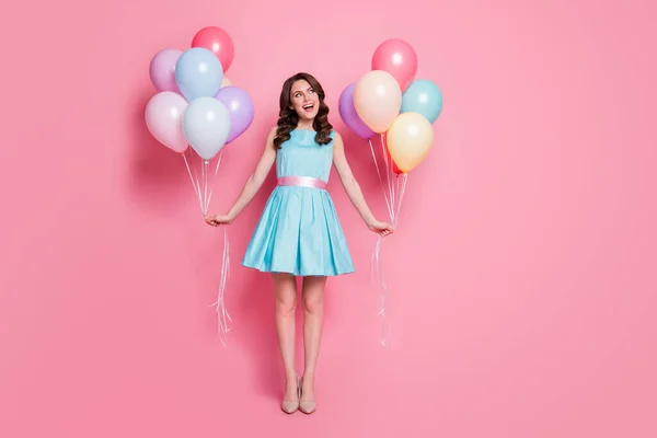 Full size photo of pretty lady festive event prom party hold both arms many air balloons dreamy look empty space wear blue mini dress skirt high-heels isolated pastel pink color background — Stock Photo, Image