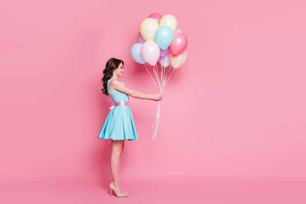 Full length body size side view of nice attractive charming smart exquisite cheerful wavy-haired girl holding in hand delivering bunch balls isolated over pink pastel color background — стоковое фото