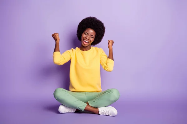 Full size photo of afro american girl sit floor legs crossed raise fists scream isolated over violet color background — Stock Photo, Image