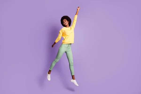 Foto de comprimento total de pele escura menina salto segurar mão copyspace desgaste pulôver calças isoladas no fundo de cor roxa — Fotografia de Stock