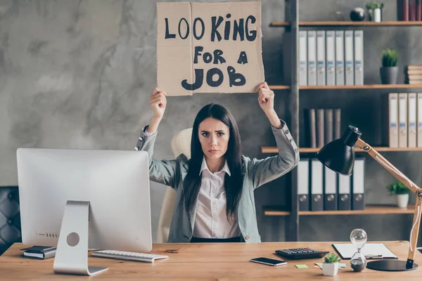 Foto di triste ragazza frustrata ha perso il suo lavoro azienda corona virus quarantena mercato crisi tenere il testo in cartone cercare lavoro indossare giacca giacca sit desk tavolo sul posto di lavoro — Foto Stock