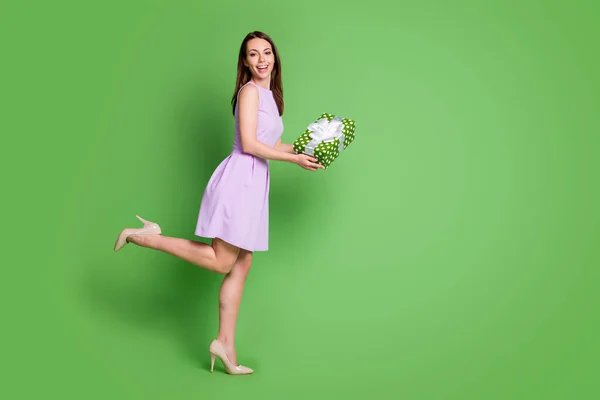 Volledige lengte lichaam grootte profiel zijaanzicht van haar ze mooi uitziende aantrekkelijk vrij charmant elegant vrolijk meisje poseren holding in handen giftbox beste verkoop geïsoleerde groene kleur achtergrond — Stockfoto