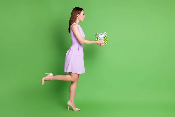 Full length body size side view of her she nice-looking attractive pretty lovely cheerful cheery glad girl posing holding in hands giftbox congrats isolated green color background — стоковое фото