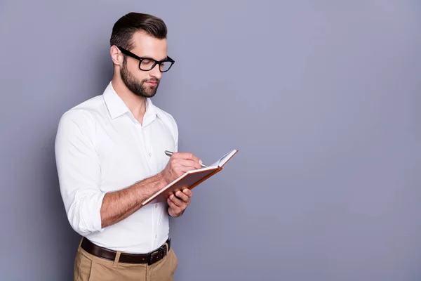 Foto retrato de un tipo inteligente concentrado en ropa formal sosteniendo una libreta abierta usándola para escribir un plan de estrategia aislado sobre un fondo gris — Foto de Stock