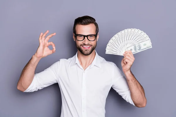 Portrait of positive cheerful manager marketer financier banker man hold usd money fan show okay sign enjoy profit lottery cashback wear white shirt isolated over gray color background — Stock Photo, Image