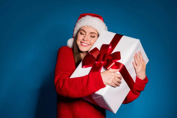 照片中的积极女孩在圣爪头戴拥抱大的白色礼品盒享受圣诞节欢乐的节日穿套头衫隔离在渐变的蓝色背景下 — 图库照片