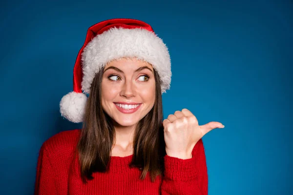 Close up foto positief meisje in santa claus hoed punt wijsvinger copyspace aanwezig x-mas nieuwjaar magie fee advertenties promo slijtage trui trui trui geïsoleerd blauw verloop kleur achtergrond — Stockfoto