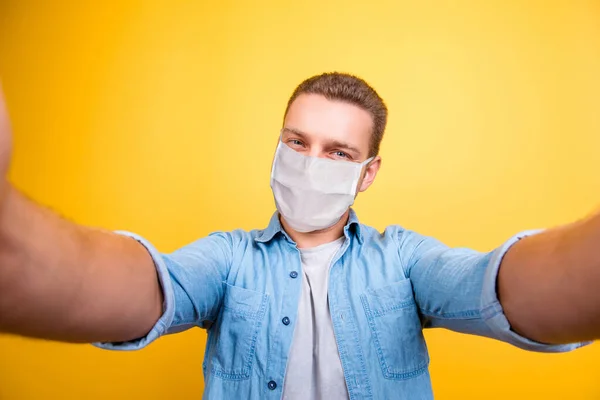 Autorretrato de chico atractivo y saludable que se divierte usando máscara de seguridad prevención de la gripe aislado sobre fondo de color amarillo brillante — Foto de Stock