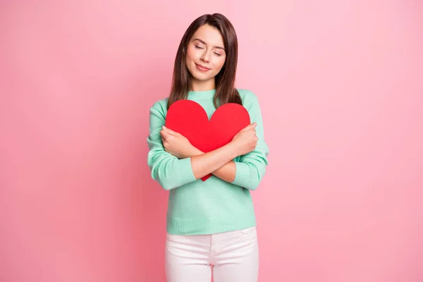 Retrato de atraente tipo sonhador calma menina segurando em mãos coração vermelho abraço isolado sobre cor pastel rosa fundo — Fotografia de Stock