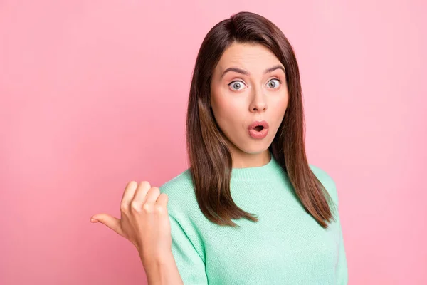 衝撃的な若い女性の写真は、親指の空のスペースを示すオープン口の摩耗ターコイズセーター孤立ピンク色の背景 — ストック写真