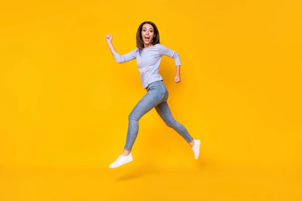 Full length body size profile side view of attractive sporty cheerful cheery girl jumping running sprint fast action activity life lifestyle isolated bright vivid shine vibrant yellow color background — Stock Photo, Image