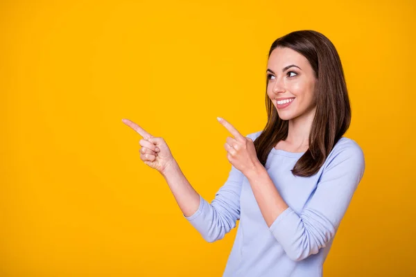 Bild av attraktiv vacker dam direkta fingrar ser sida tomt utrymme gott humör visar nyhet banner shopping försäljning rabatt bära casual shirt isolerad gul färg bakgrund — Stockfoto