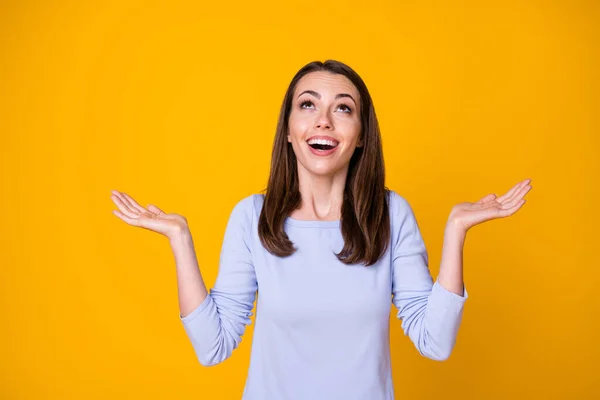 Photo of attractive pretty happy lady good mood open mouth excited overjoyed look up empty space sky catch arms rain drops wear casual shirt isolated vibrant yellow color background — Zdjęcie stockowe