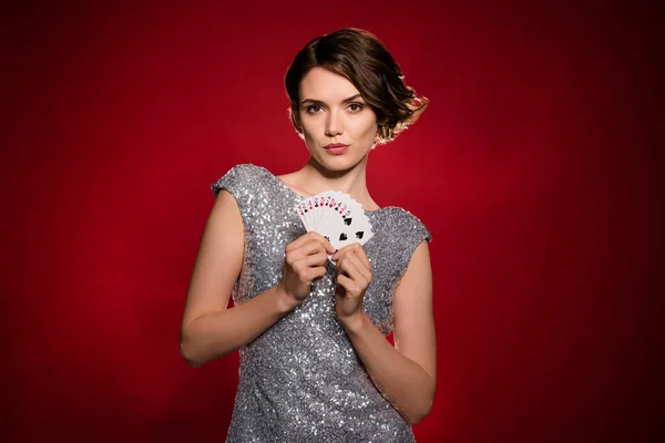 Photo of attractive lady professional casino poker player hold cards risky gamer all in cheating bluffing opening combination wear shine dress isolated dark red gradient color background