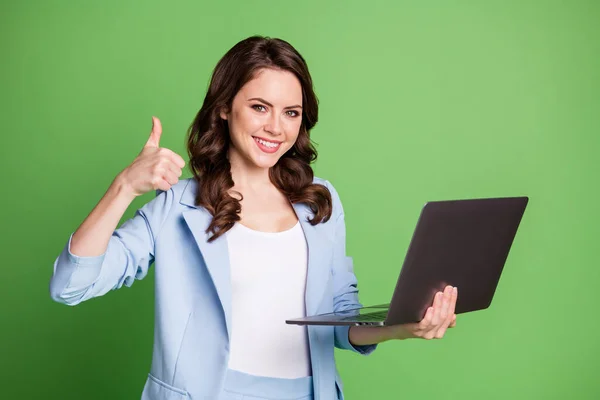 Portret inteligentnej menedżerki HR utrzymanie laptopa uśmiechnięty pokazując kciuk-up noszenie niebieski formalny blezer izolowany na żywe zielone tło — Zdjęcie stockowe