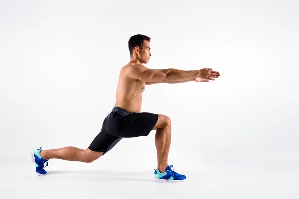 Full length profile photo of handsome sportsman dark skin guy naked chest doing cardio exercise focused hands help balancing lunges wear shorts sneakers isolated white color background — Stock Photo, Image