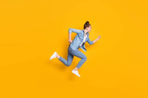 Full body profile photo of attractive teen lady jumping high up running race marathon excited to win rushing wear casual denim shirt sneakers pants isolated yellow color background — Stock Photo, Image