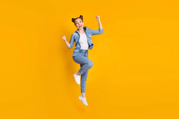 Corpo inteiro foto de atraente adolescente senhora saltando alto para cima celebrando favorito esportes equipe ganhar cheerleader levantar punhos desgaste casual jeans camisa sapatilhas calças isoladas cor amarela fundo — Fotografia de Stock