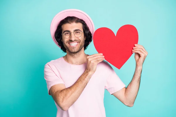 Retrato de romántico tipo divertido que muestra corazón de papel desgaste rosa gorra camiseta gafas aisladas sobre fondo de color verde azulado — Foto de Stock