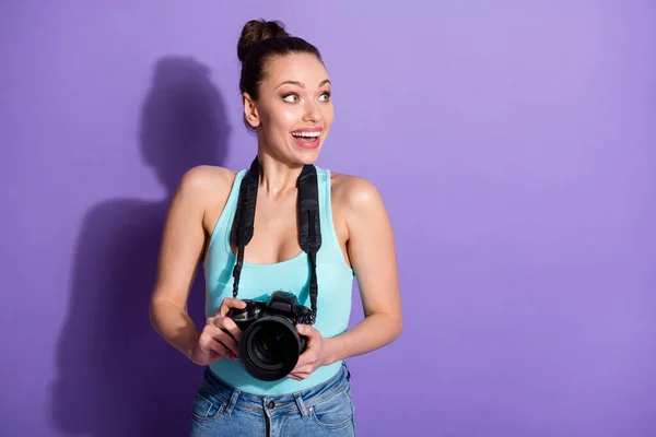 Portrait of positive cheerful crazy girl tourist hold digital camera look copyspace disappeared incredible summer discount wear singlet denim jeans isolated over purple color background — Stok Foto