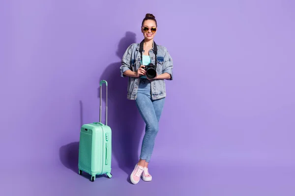 Teljes test fotó pozitív vidám lány turista hold fénykép kamera poggyász kész utazás repülőtér külföldön viselnek singlet tornacipő elszigetelt lila színű háttér — Stock Fotó