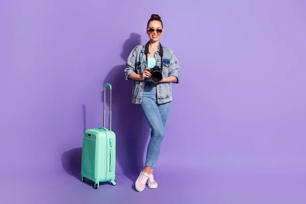 Foto de cuerpo completo de chica alegre positiva bodega de turistas equipaje de la cámara de fotos listo viaje aeropuerto en el extranjero usar zapatillas de deporte de singlet aislado sobre fondo de color púrpura —  Fotos de Stock